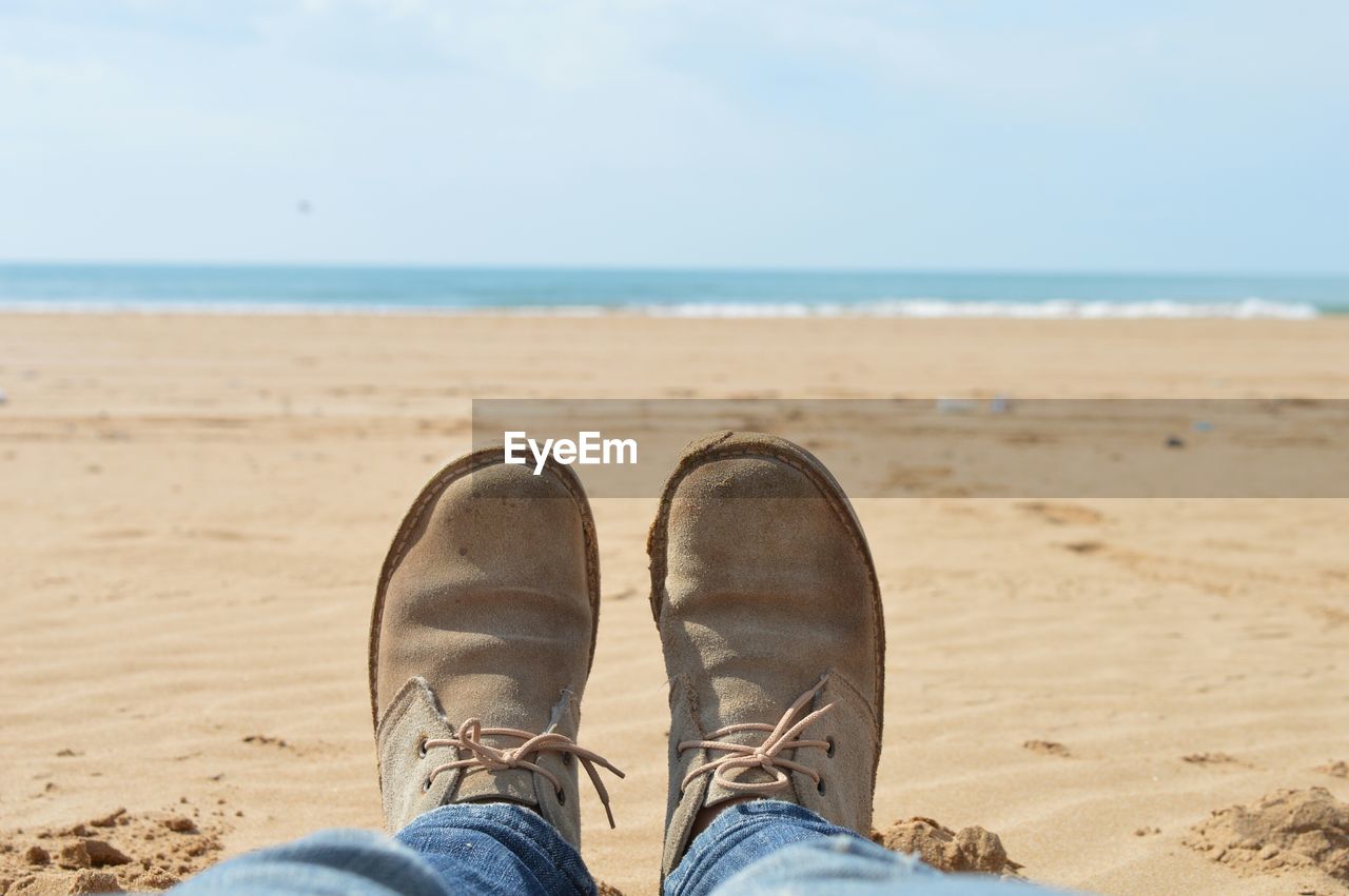 View of men's feet with seascape in background