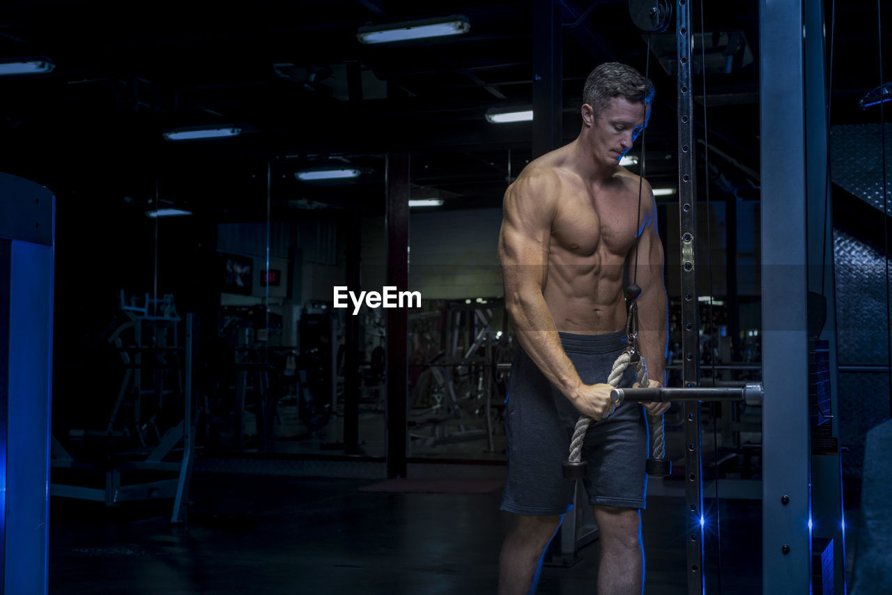 FULL LENGTH OF SHIRTLESS YOUNG MAN STANDING IN ROOM