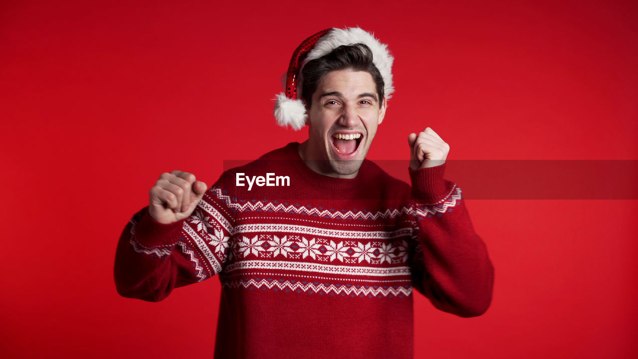 Portrait of young man shouting against red background