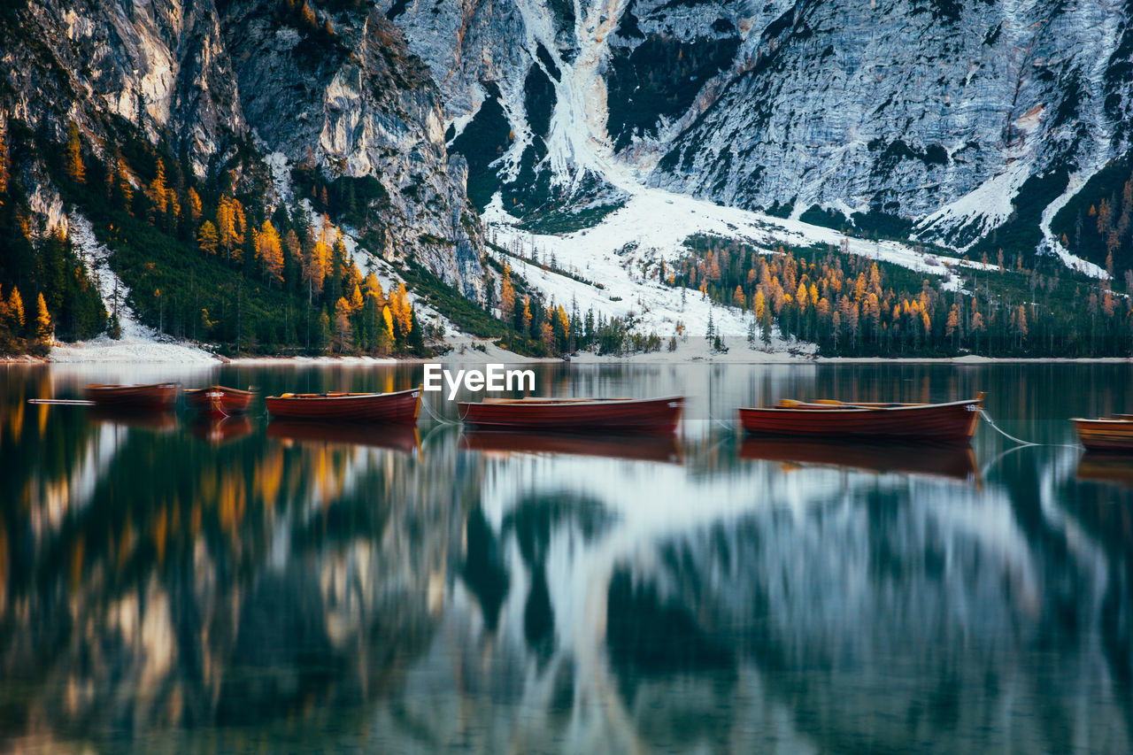 Boats in lake against snowcapped mountains