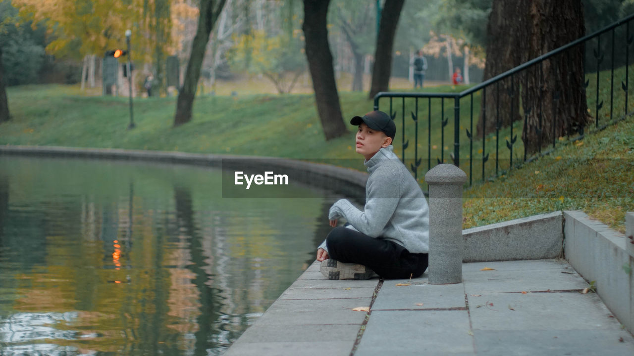 side view of young man sitting on railing