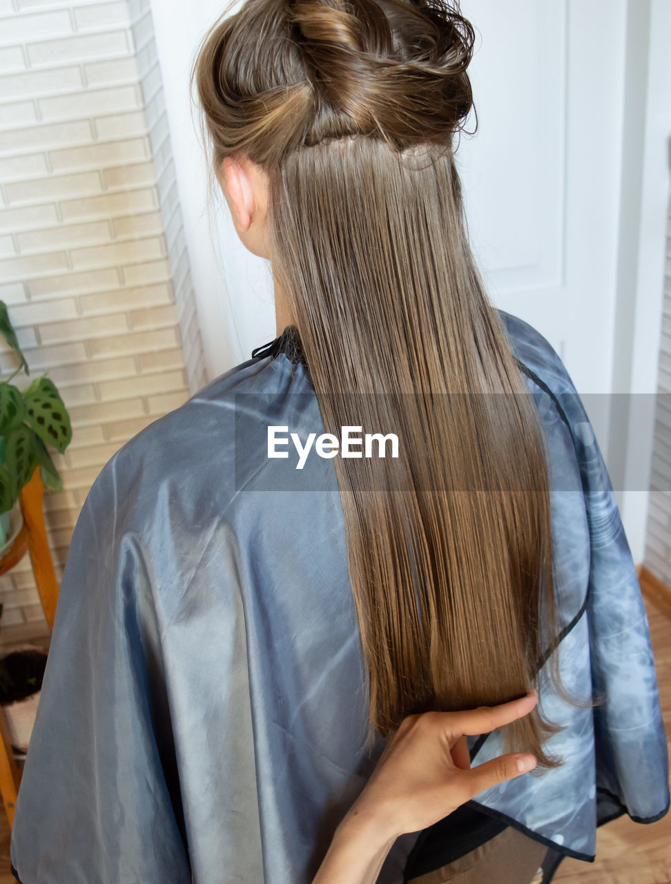 Woman hairdresser cuts wet long hair with scissors at home