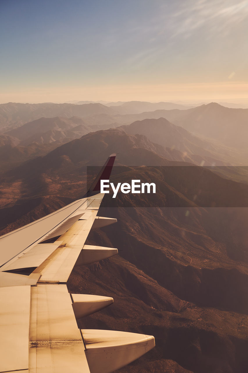 Scenic view of mountains against sky during sunset out of plane window