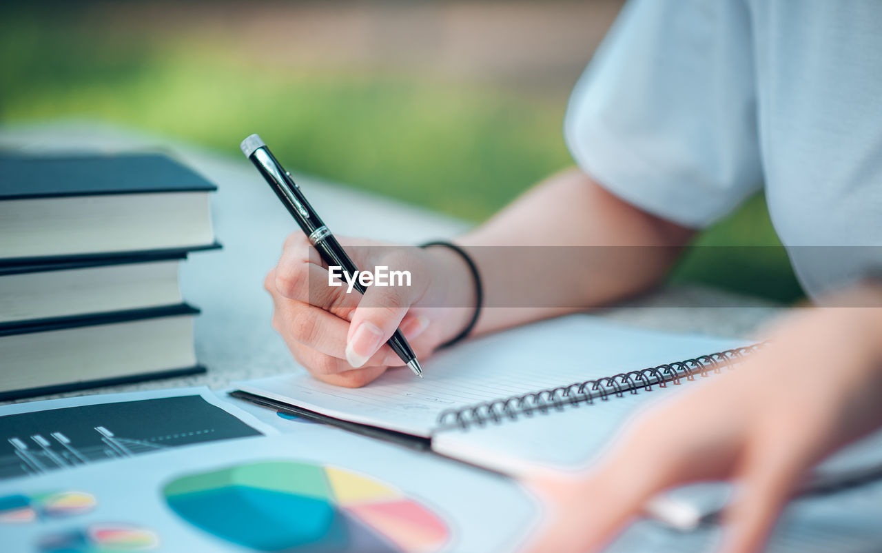 Midsection of woman writing in book