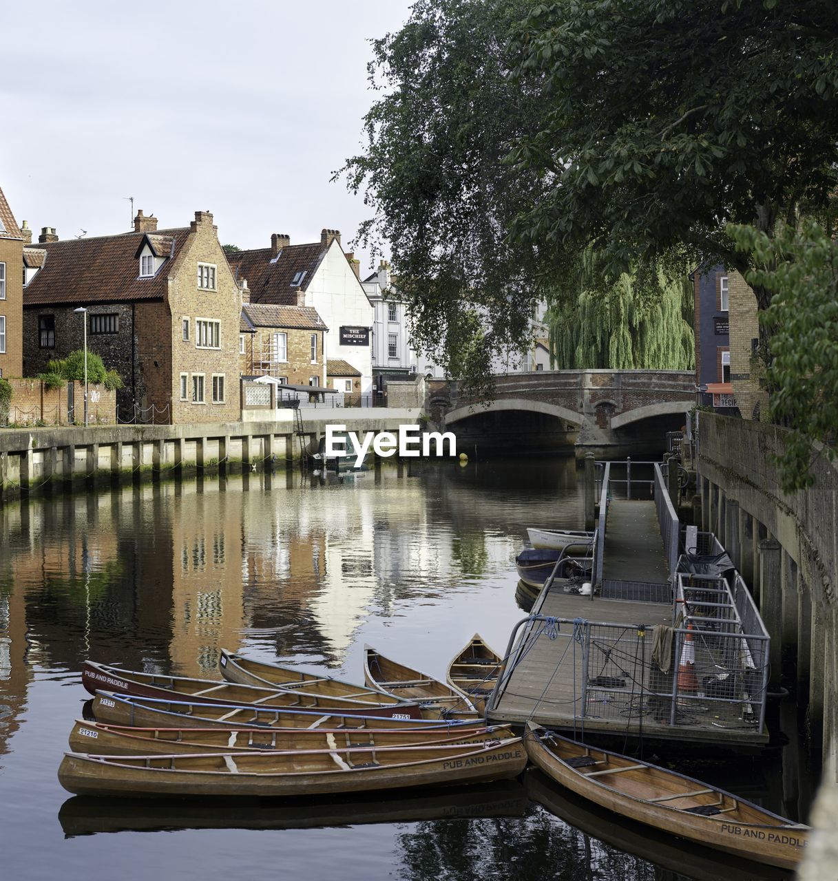 BOATS MOORED IN RIVER BY BUILDINGS AGAINST HOUSES