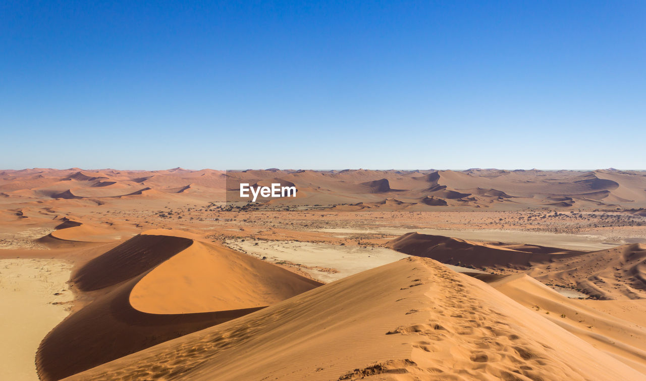 Scenic view of desert against clear blue sky