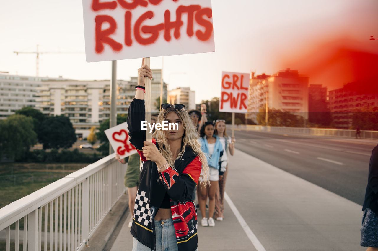 Women with posters marching for equal rights against sky in city