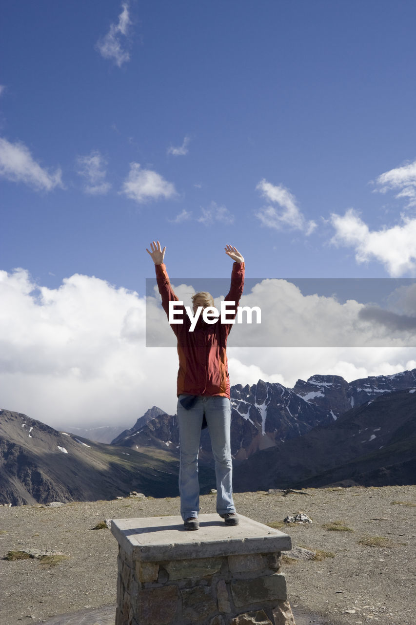 Portrait of woman with arms raised while standing on whistler mountain against sky