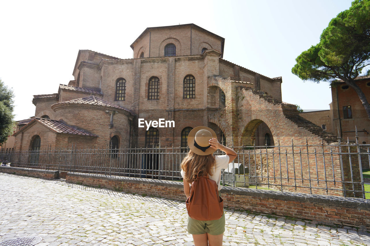 Rear view of woman looking at building against sky