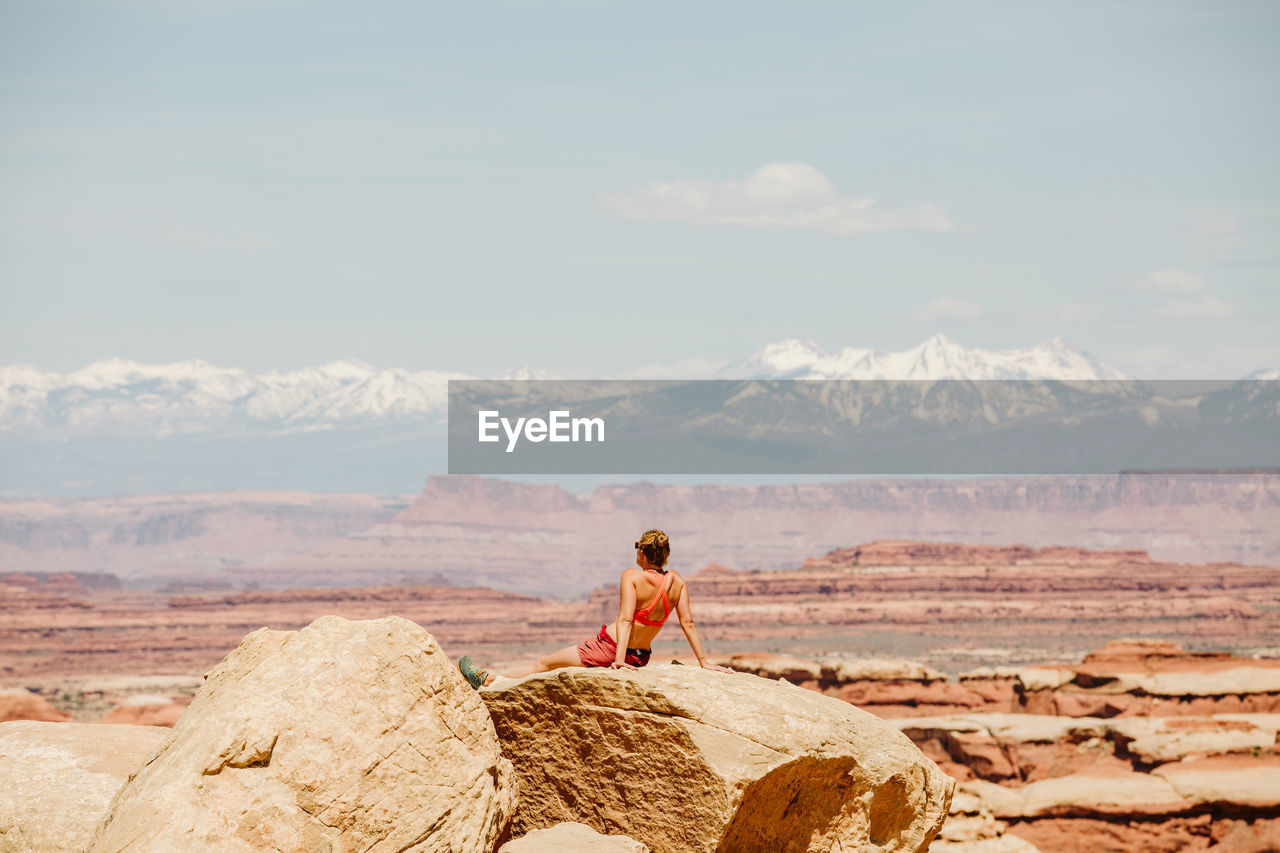 Female hiker in sports bra relaxes at a viewpoint in the maze utah