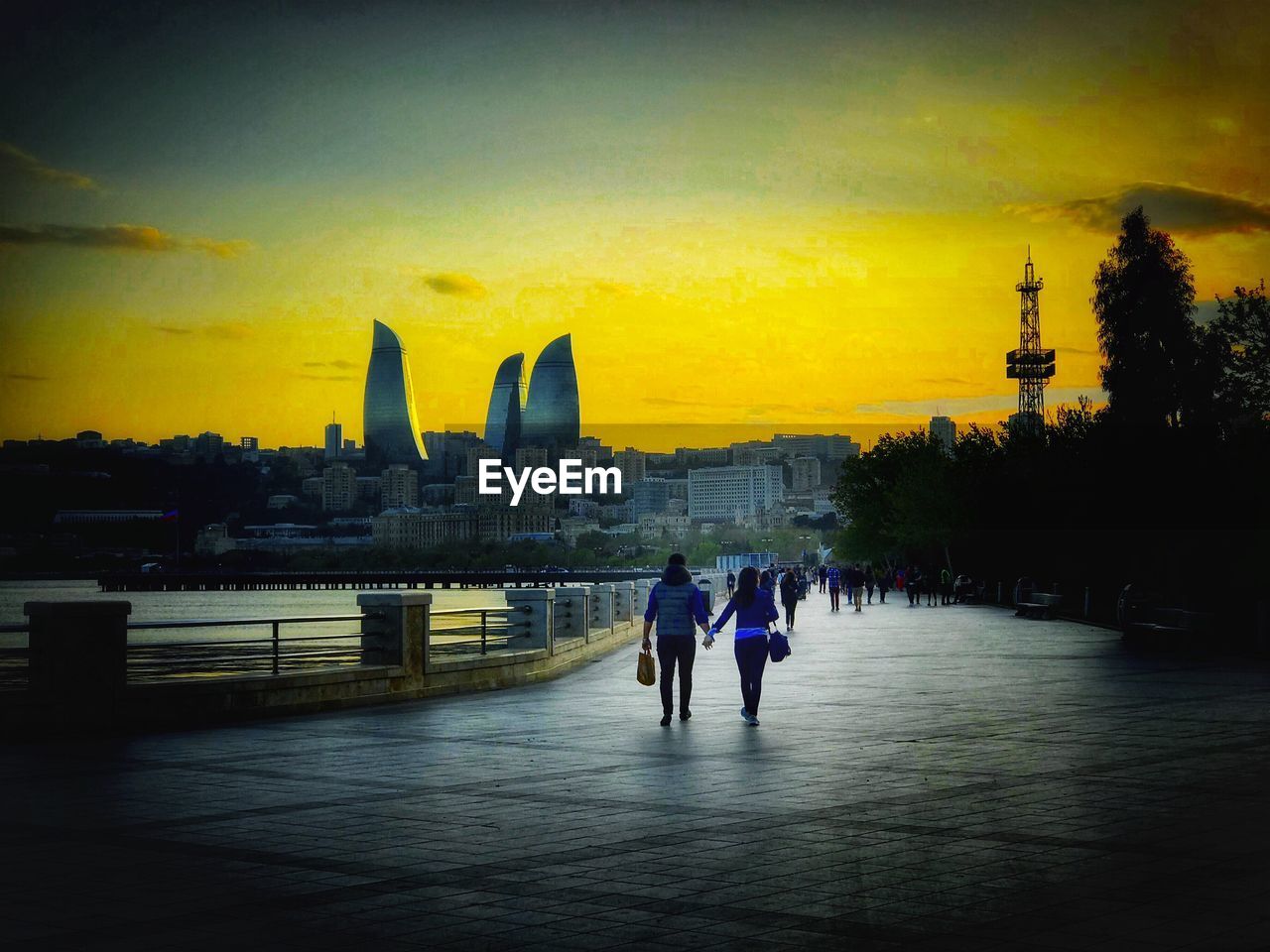 PEOPLE WALKING IN FRONT OF BUILDINGS AT SUNSET