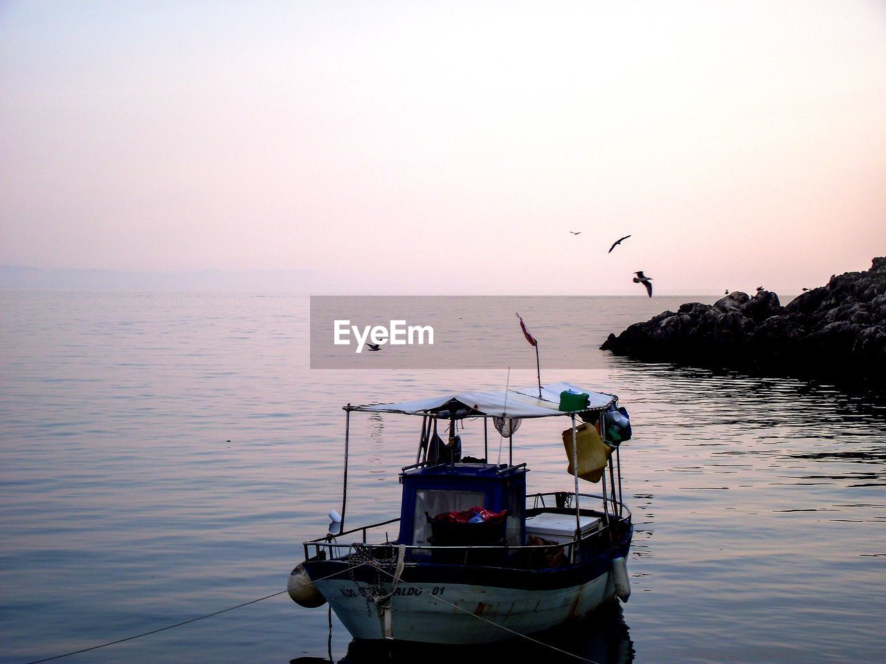 Fishing boats in sea against sky during sunset