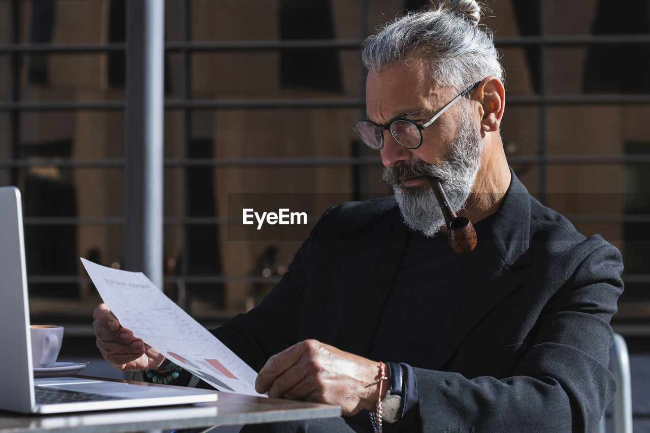 Serious male entrepreneur looking at business plan while sitting in cafe