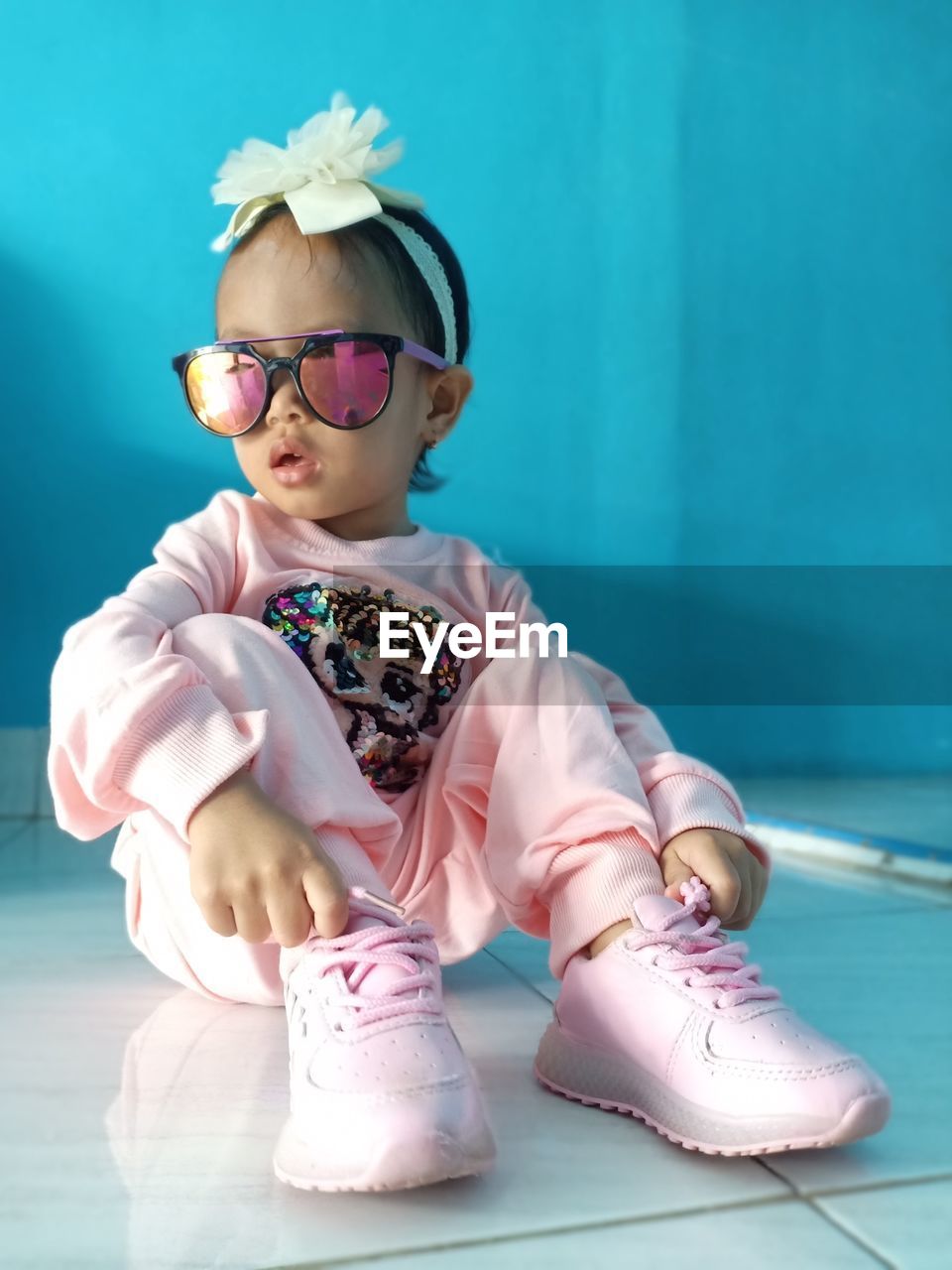 Cute girl in sunglasses sitting on floor at home