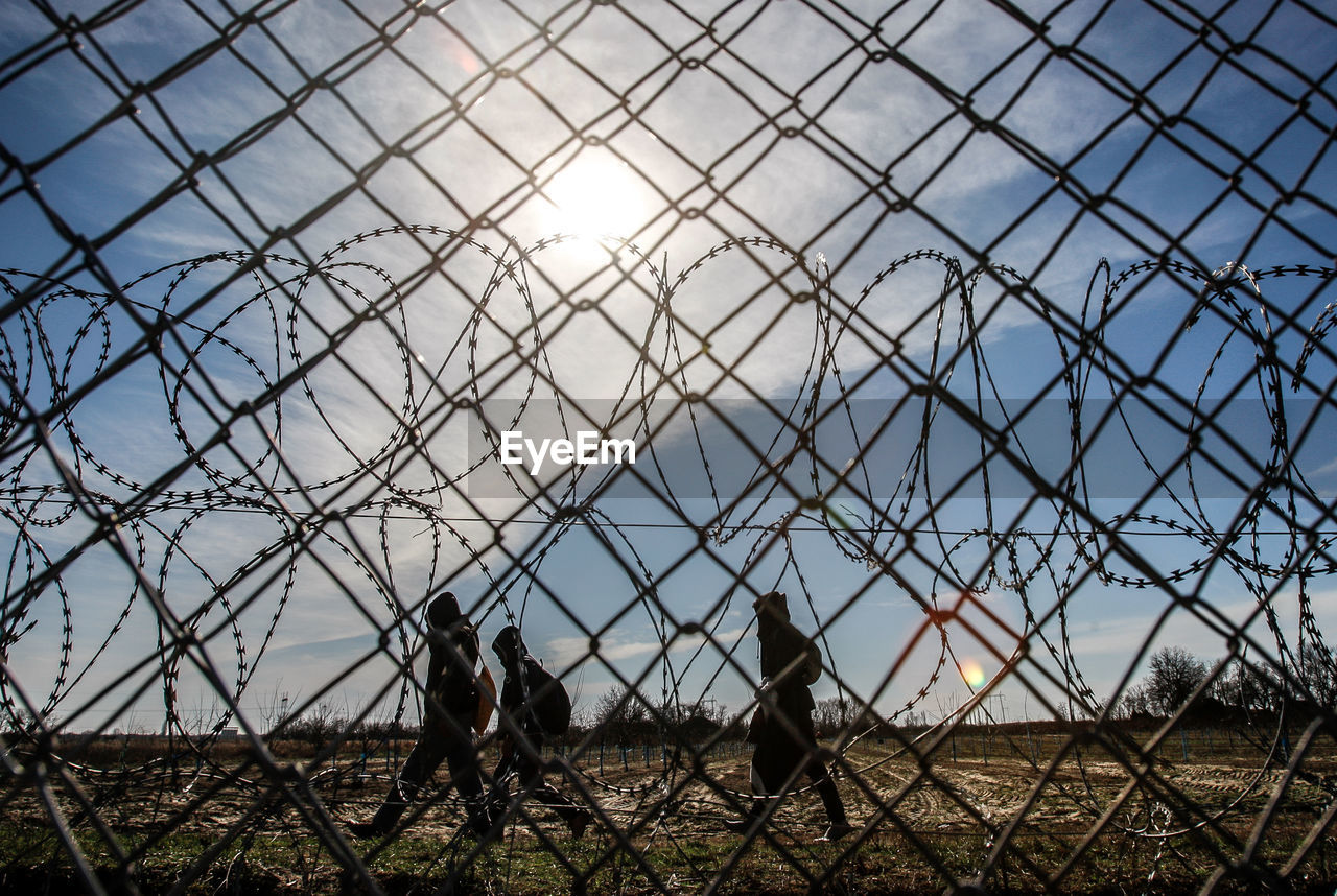 SUN SHINING THROUGH CHAINLINK FENCE