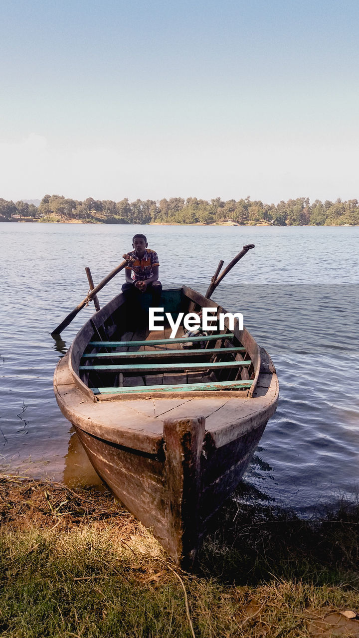 MAN IN BOAT ON SEA AGAINST SKY