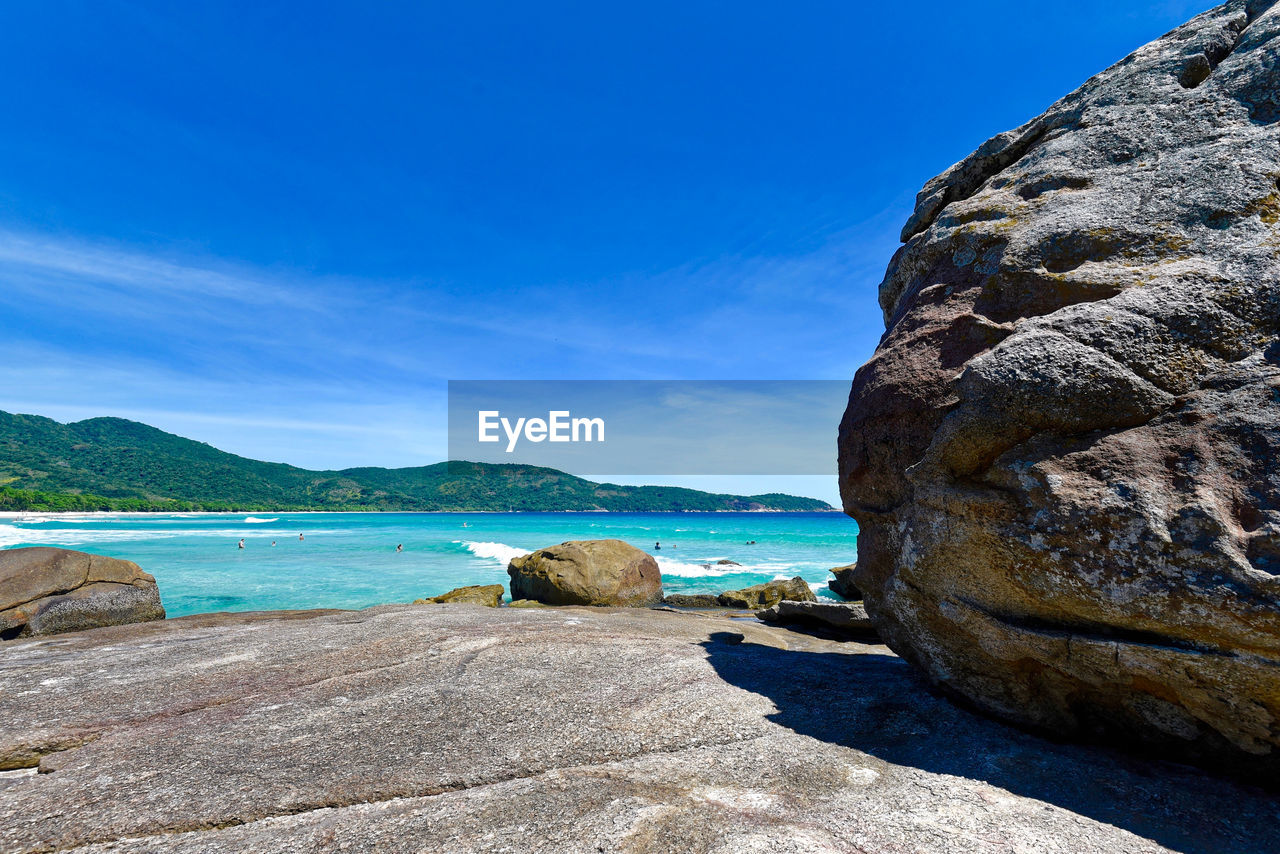 Rock formation on beach against blue sky