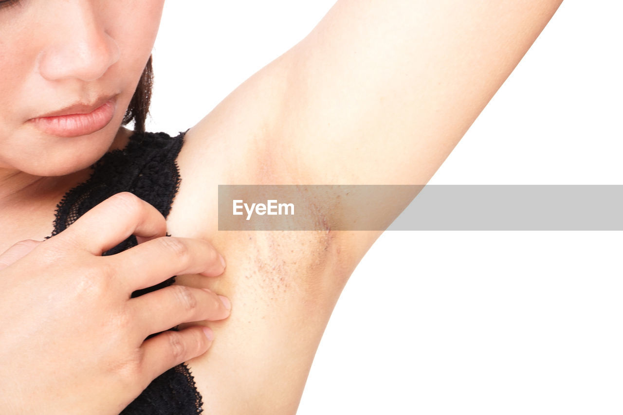 Cropped image of woman looking under the arm against white background
