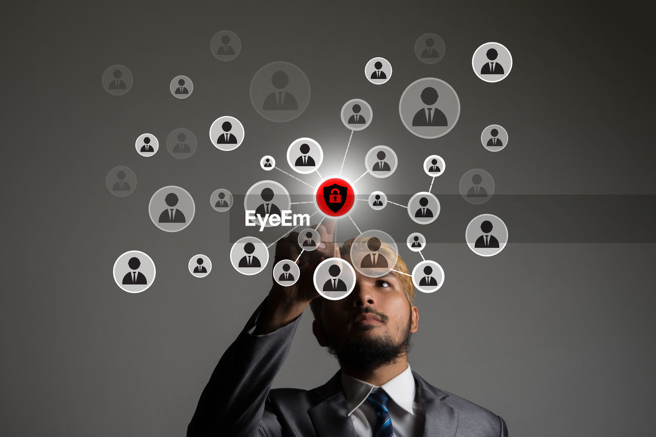 Digital composite image of businessman operating icons against gray background