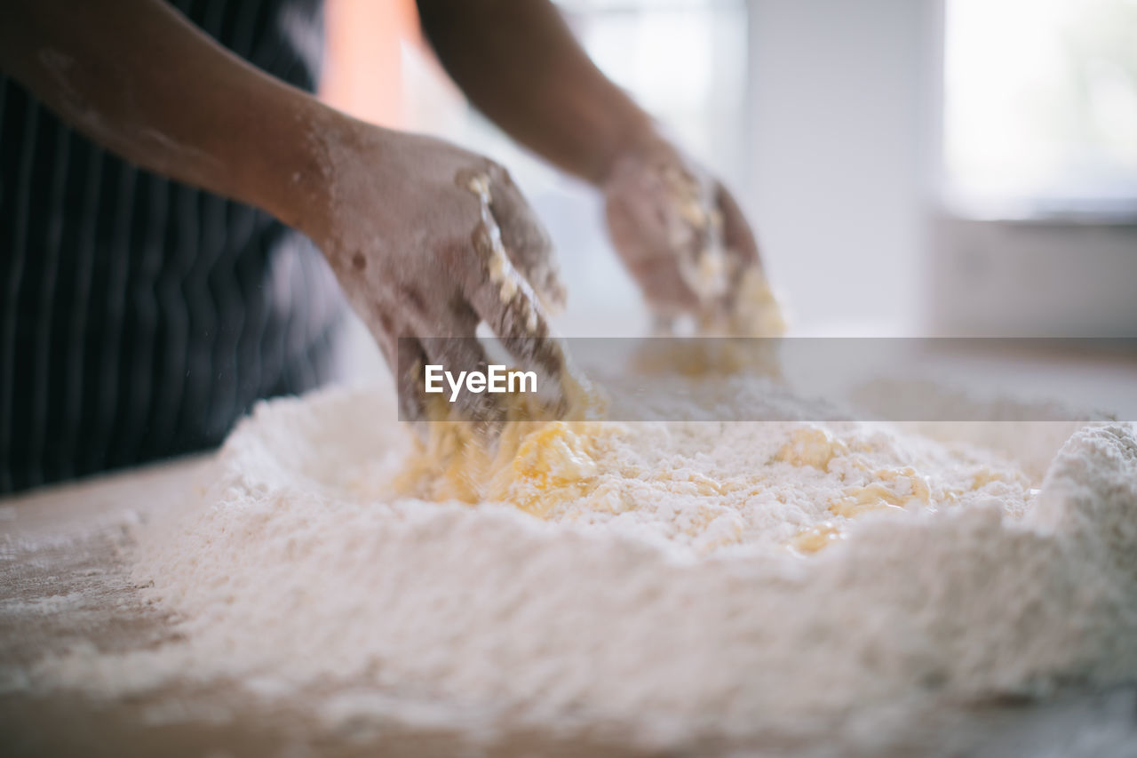 CLOSE-UP OF PERSON PREPARING FOOD ON TABLE