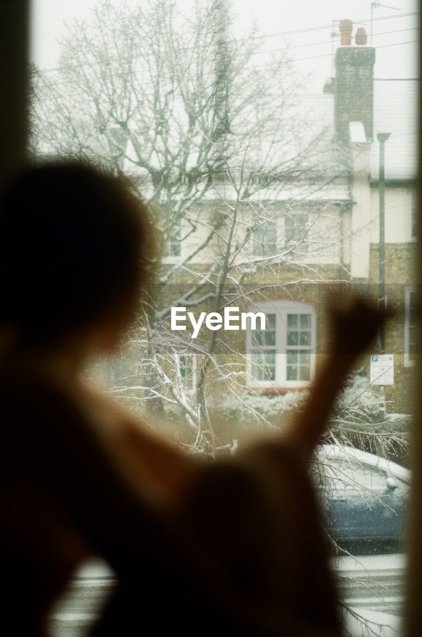 REAR VIEW OF WOMAN SEEN THROUGH GLASS WINDOW