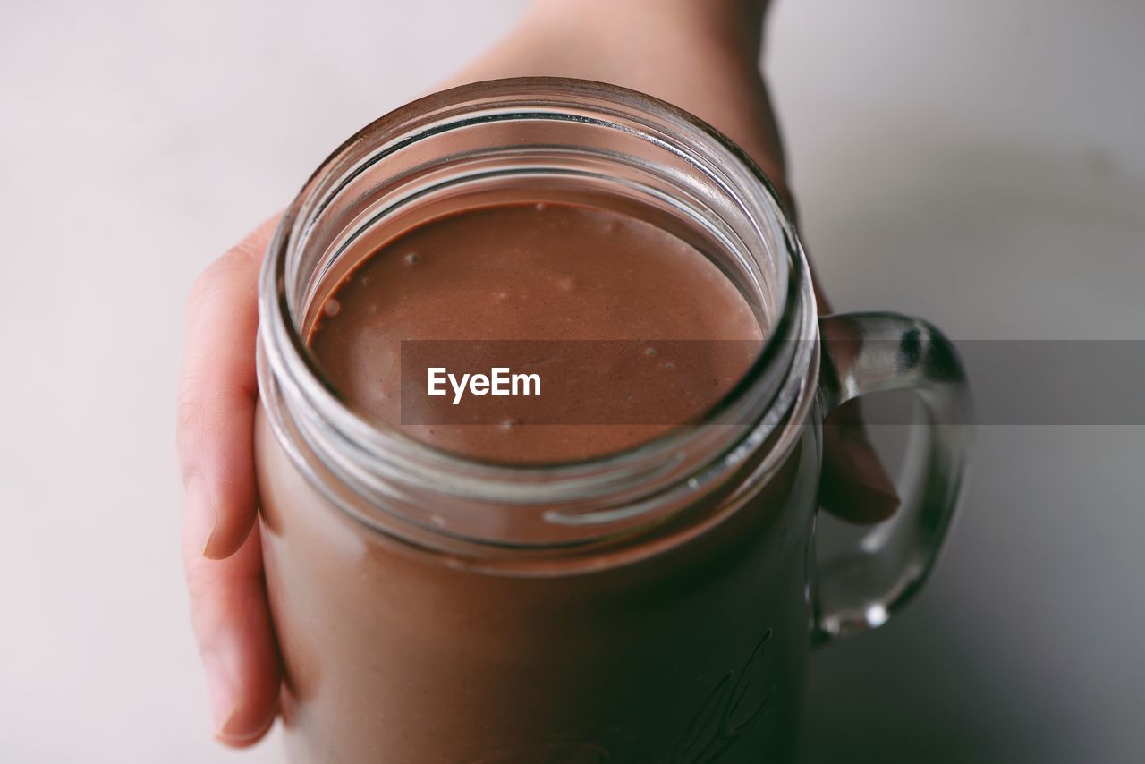 Close-up of hand holding coffee on table