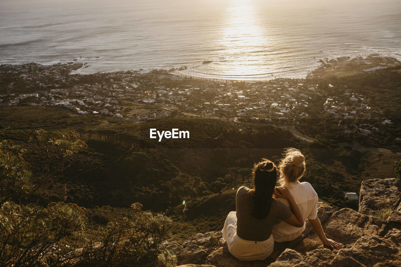 Friends admiring sea sitting on rock at signal hill