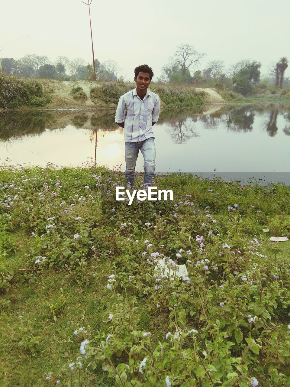 Man standing on field at lake