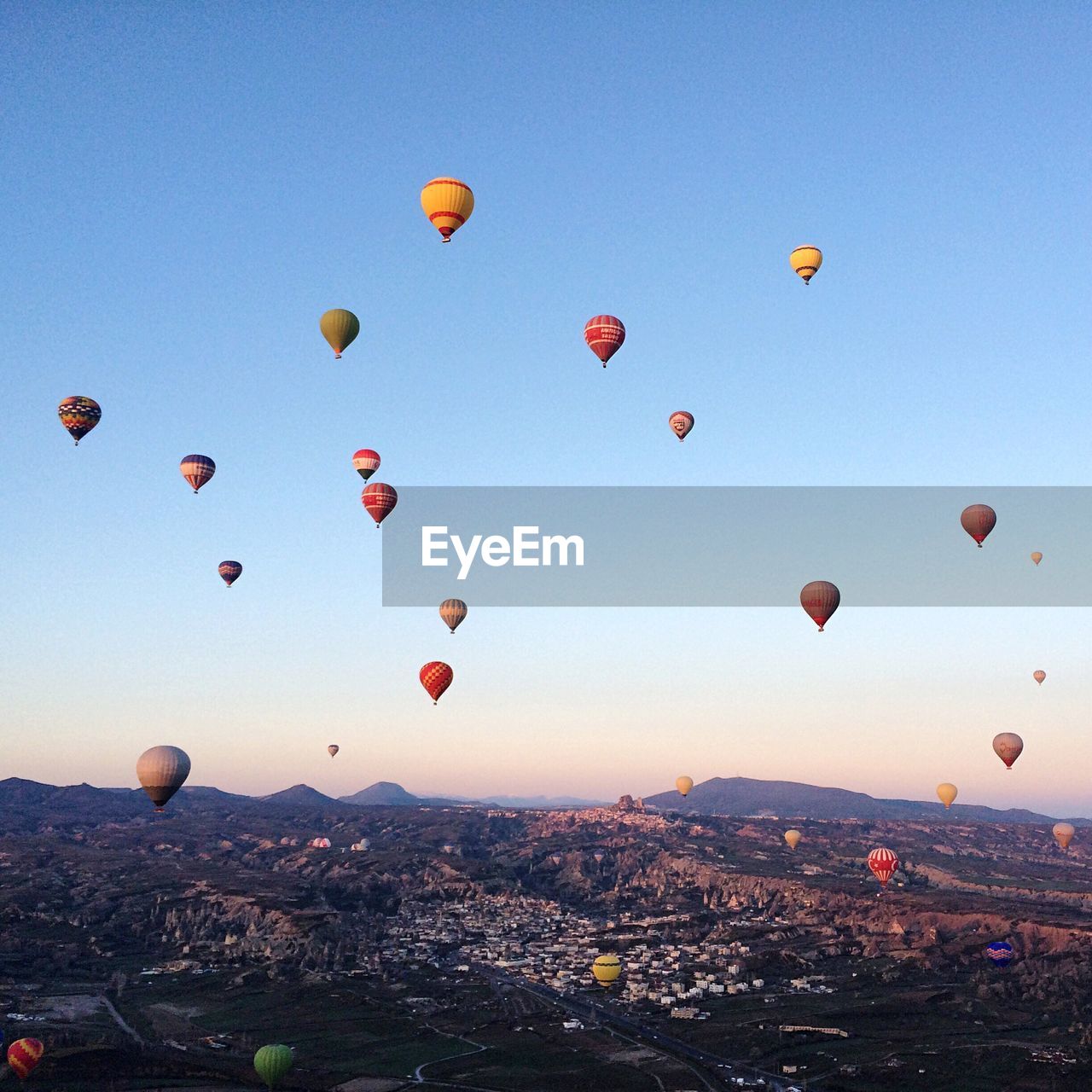 Hot air balloons flying above landscape against blue sky