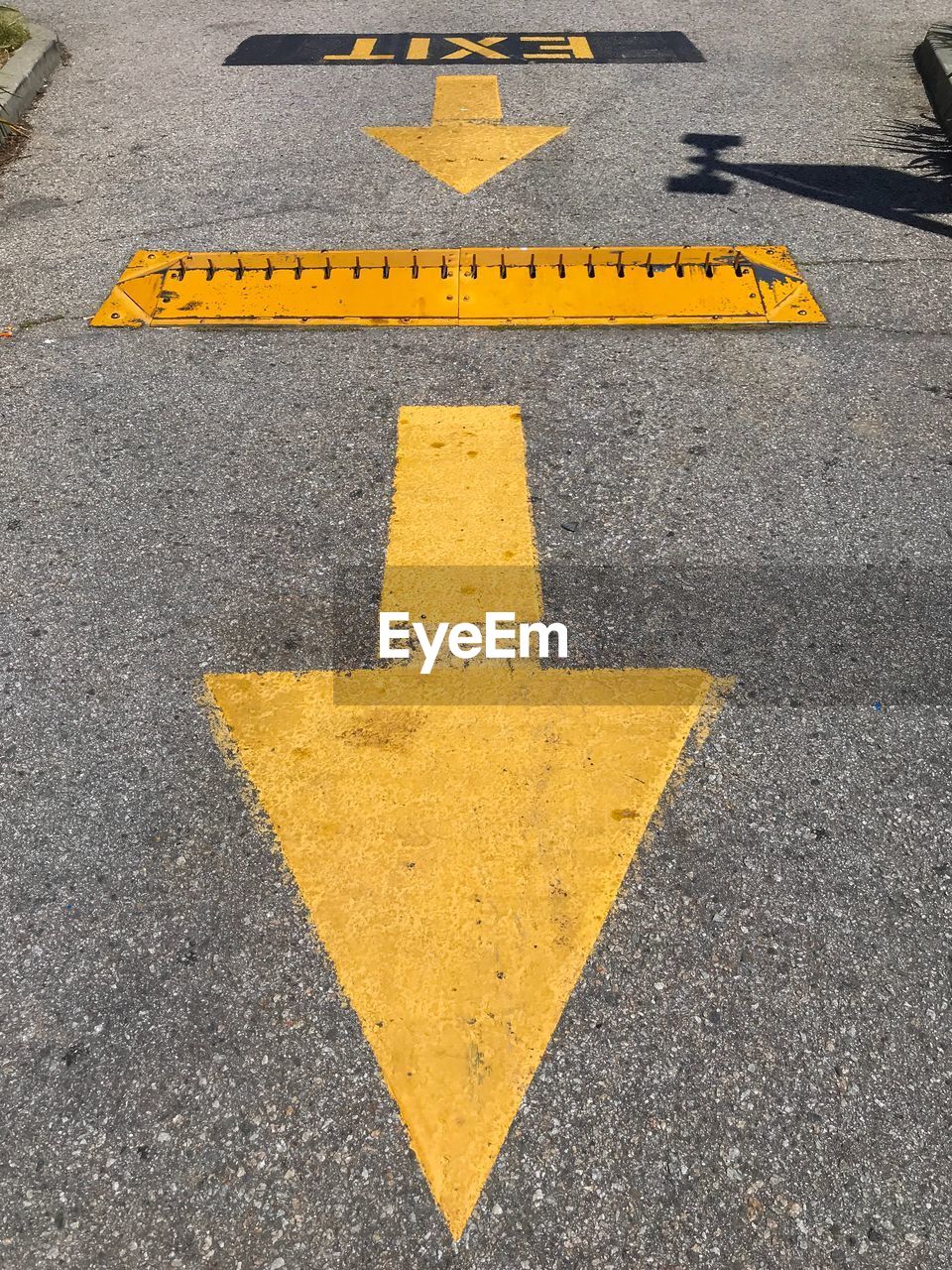 HIGH ANGLE VIEW OF ARROW SYMBOL ON ROAD