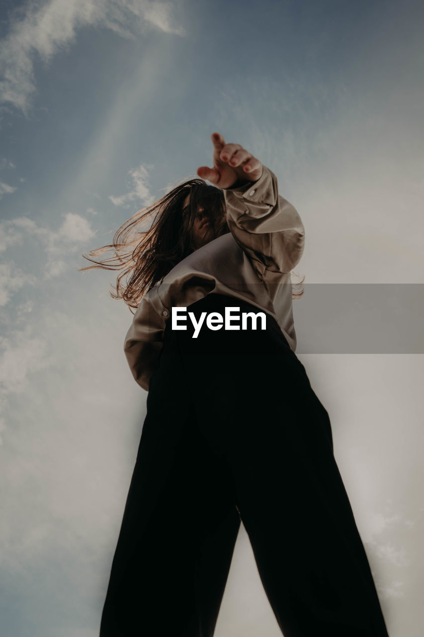 Low angle view of woman standing against sky