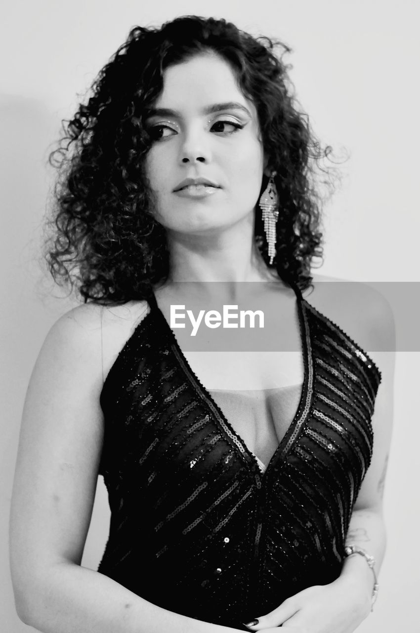 one person, black and white, black, portrait, women, adult, curly hair, hairstyle, monochrome photography, white, photo shoot, young adult, looking at camera, studio shot, monochrome, fashion, indoors, portrait photography, waist up, long hair, front view, brown hair, person, clothing, dress, female, elegance, white background, standing, human hair, glamour, lifestyles, looking, serious, individuality