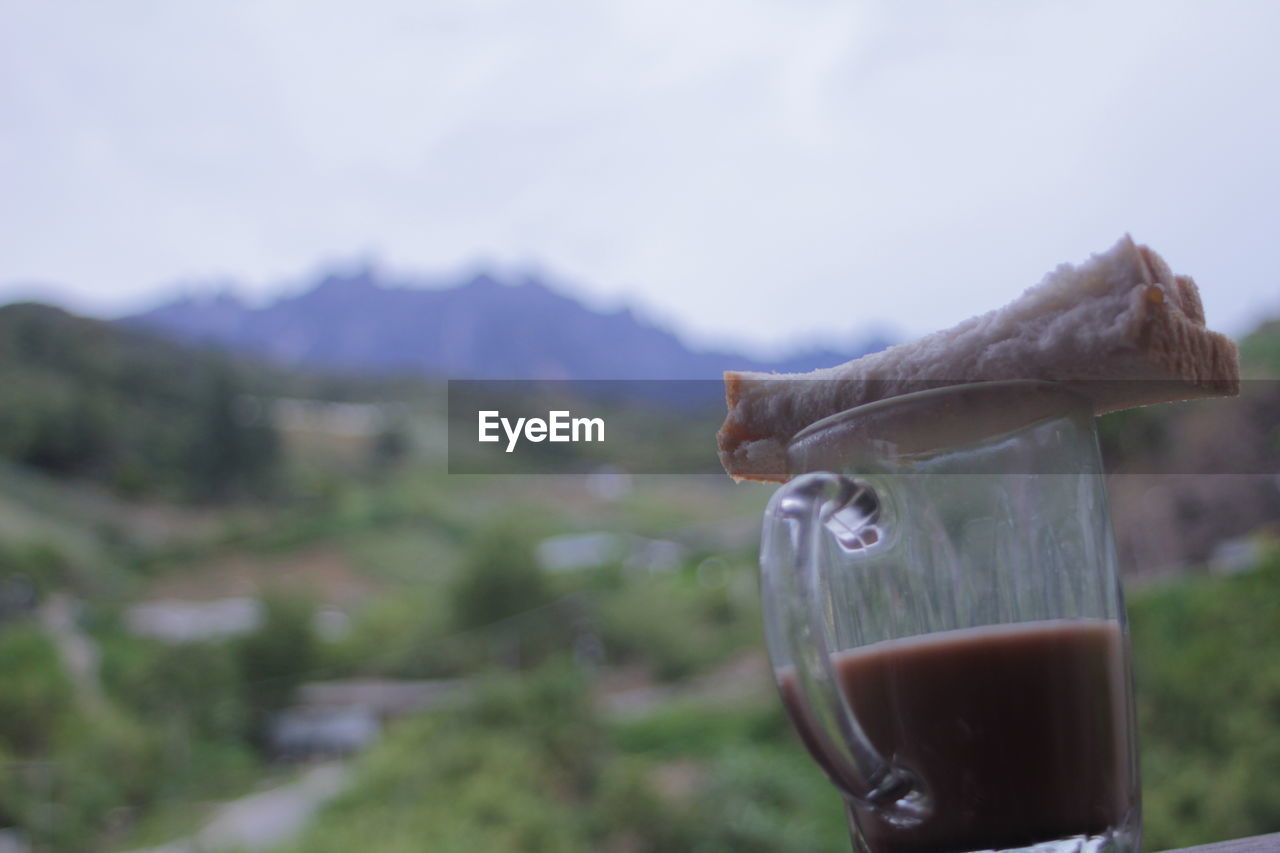 CLOSE-UP OF DRINK AGAINST MOUNTAIN