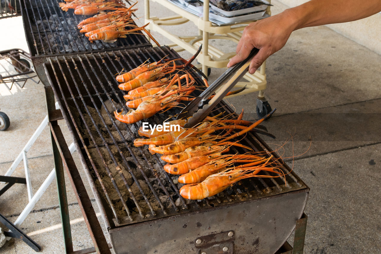 MAN PREPARING FOOD ON BARBECUE GRILL