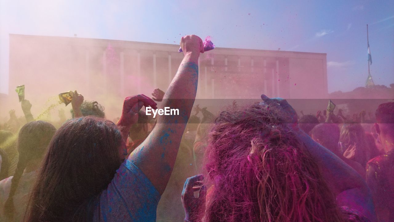 People playing holi on street against sky