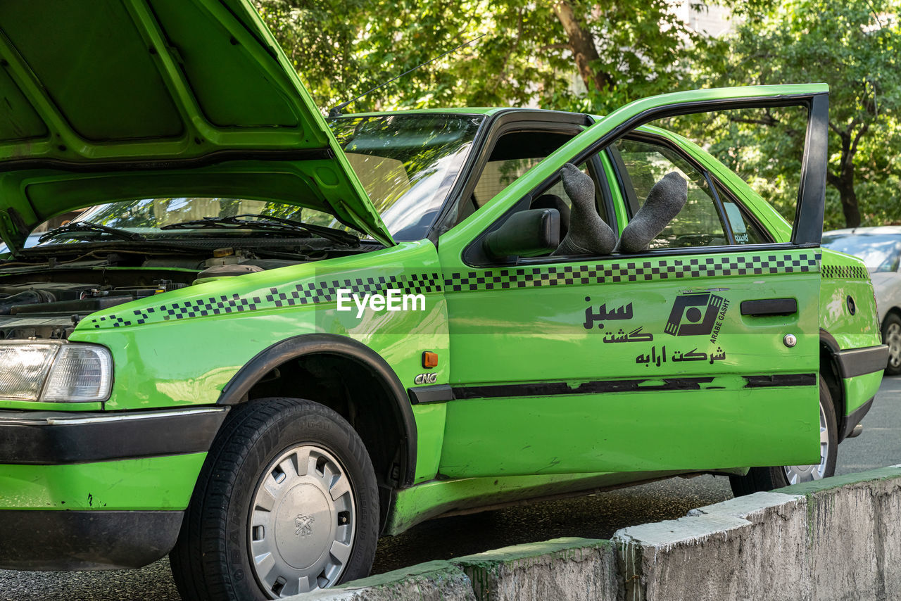 SIDE VIEW OF OLD VINTAGE CAR ON GREEN LANDSCAPE