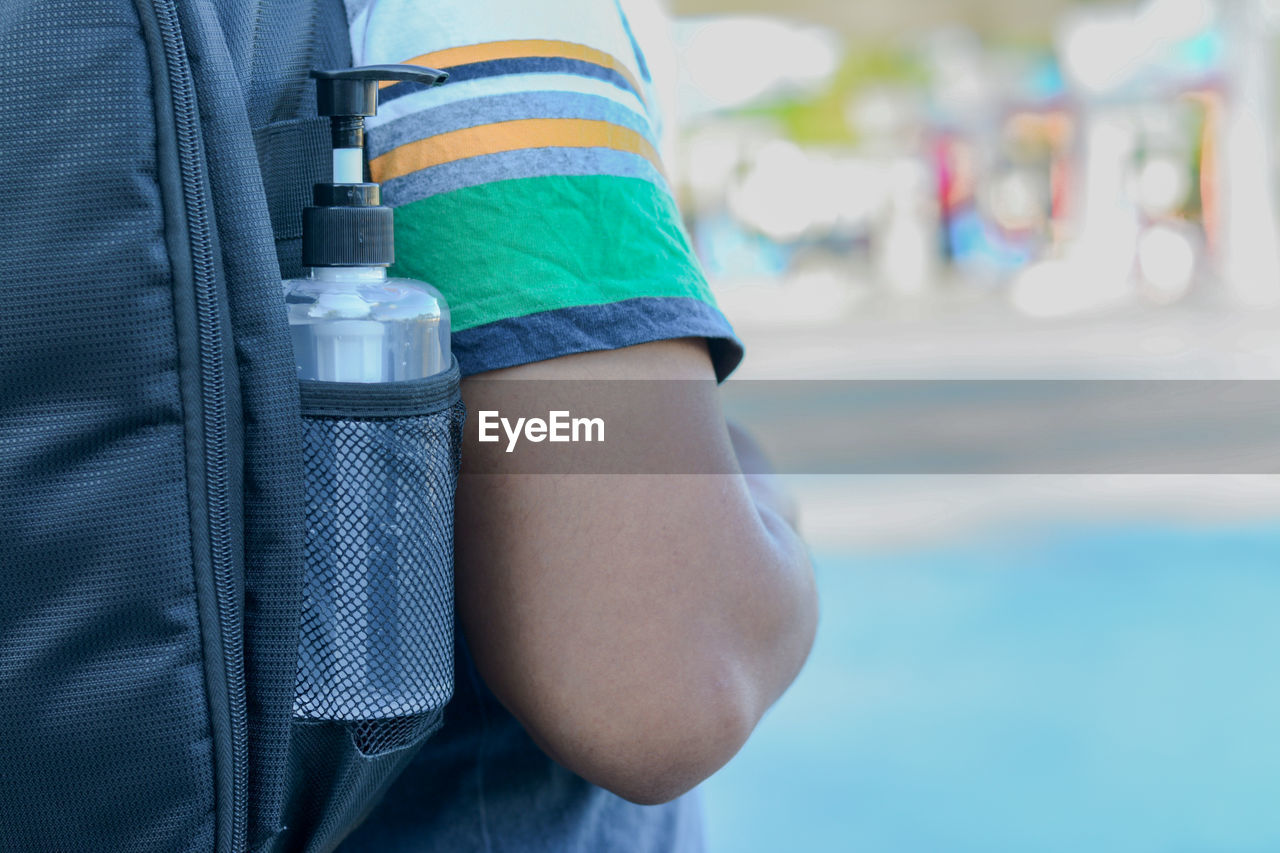 Midsection of boy with backpack and bottle