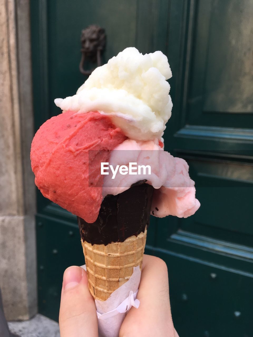 Cropped hand of person holding ice cream against closed door