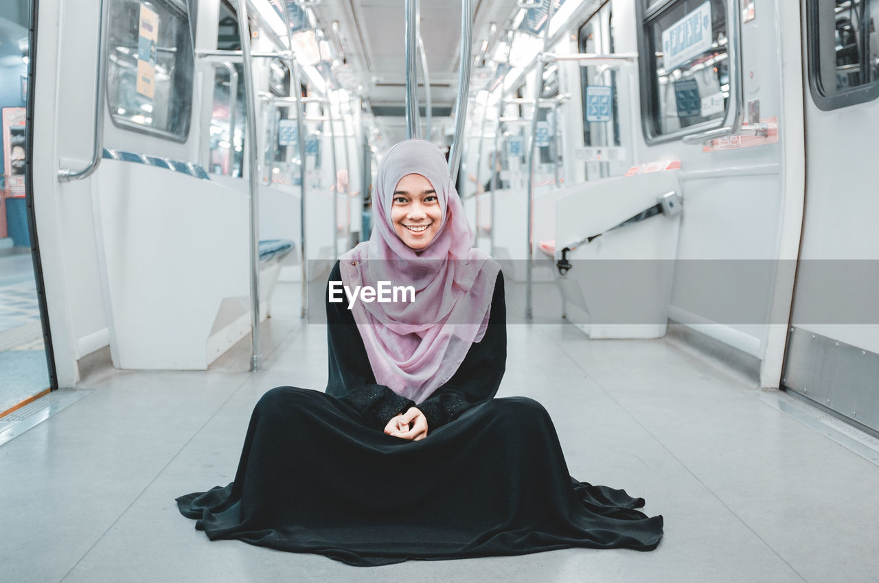 Portrait of smiling young woman wearing religious dress while sitting in train