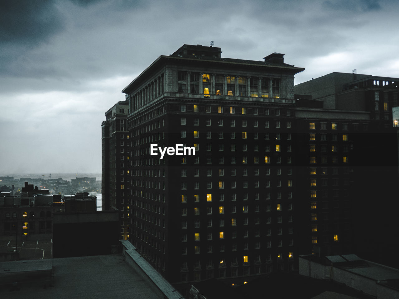 LOW ANGLE VIEW OF ILLUMINATED BUILDINGS AGAINST CLOUDY SKY