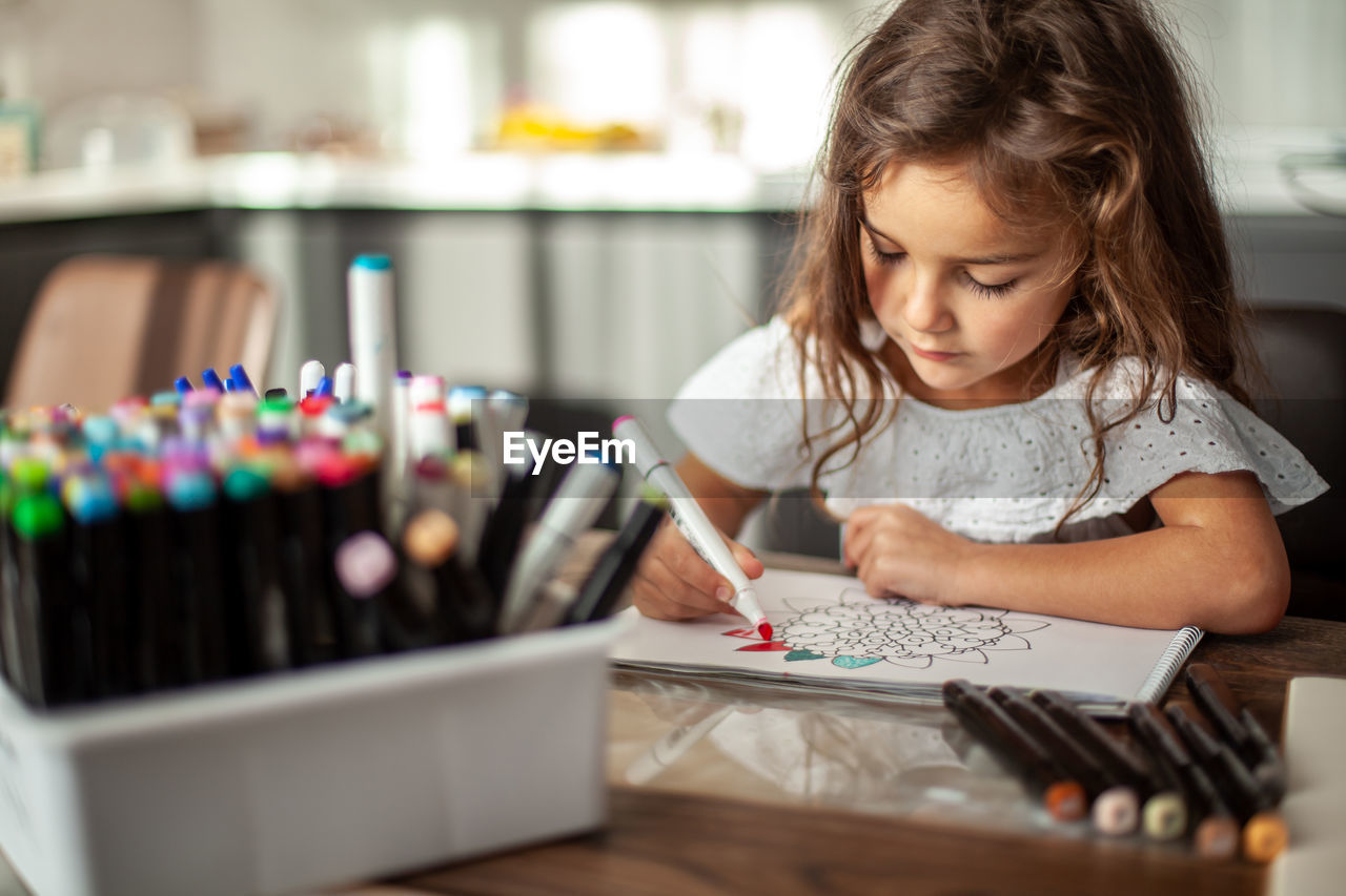 Cute girl drawing on book