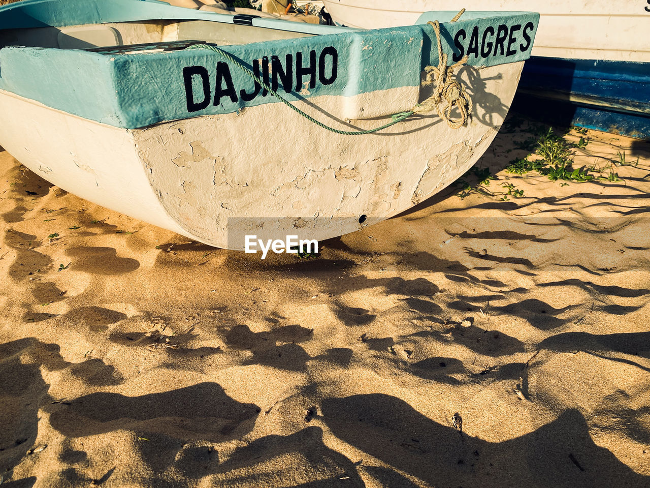 sand, beach, land, vehicle, boat, nautical vessel, text, nature, no people, water, day, sunlight, transportation, western script, mode of transportation, moored, outdoors, sea, wood, watercraft, communication