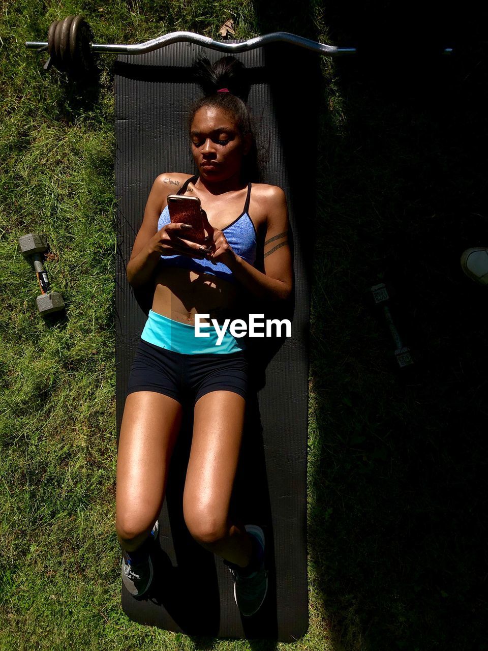 Young woman using phone while lying on grass