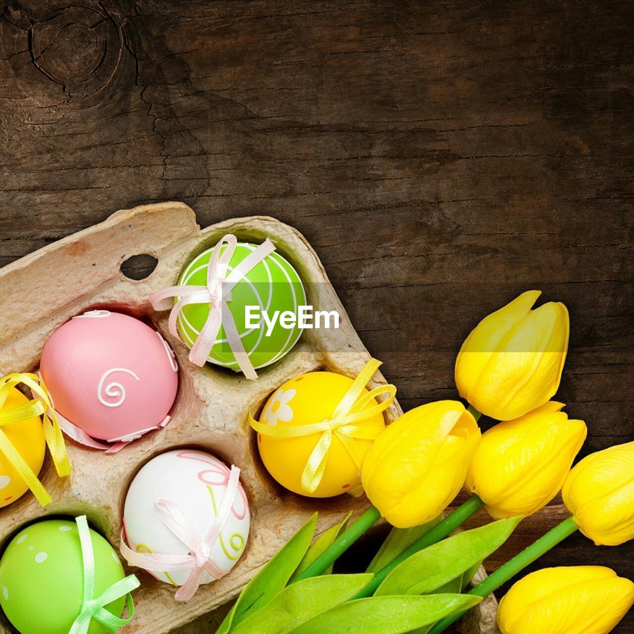 Directly above shot of yellow tulips by easter eggs on table