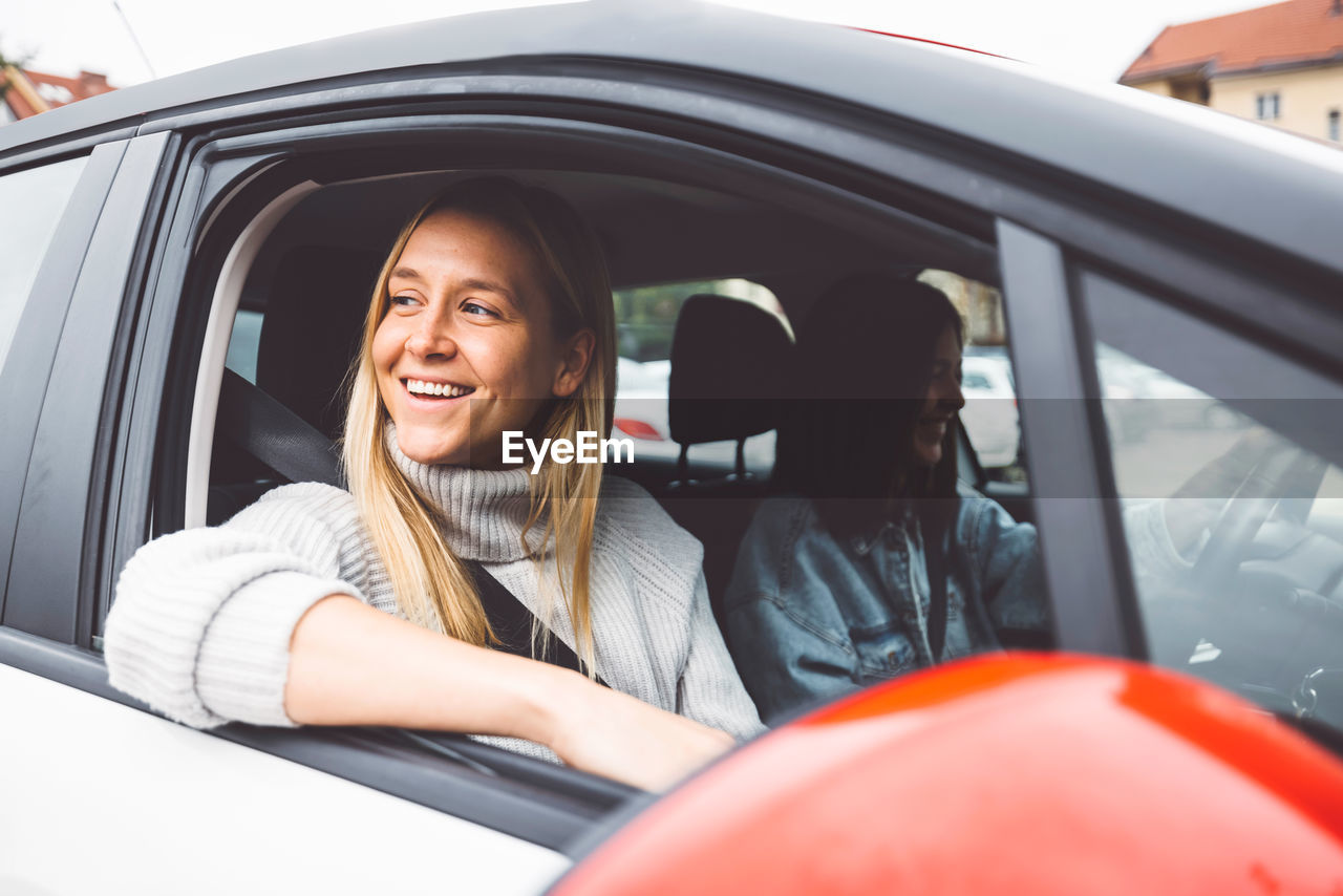 portrait of smiling young woman with dog in car