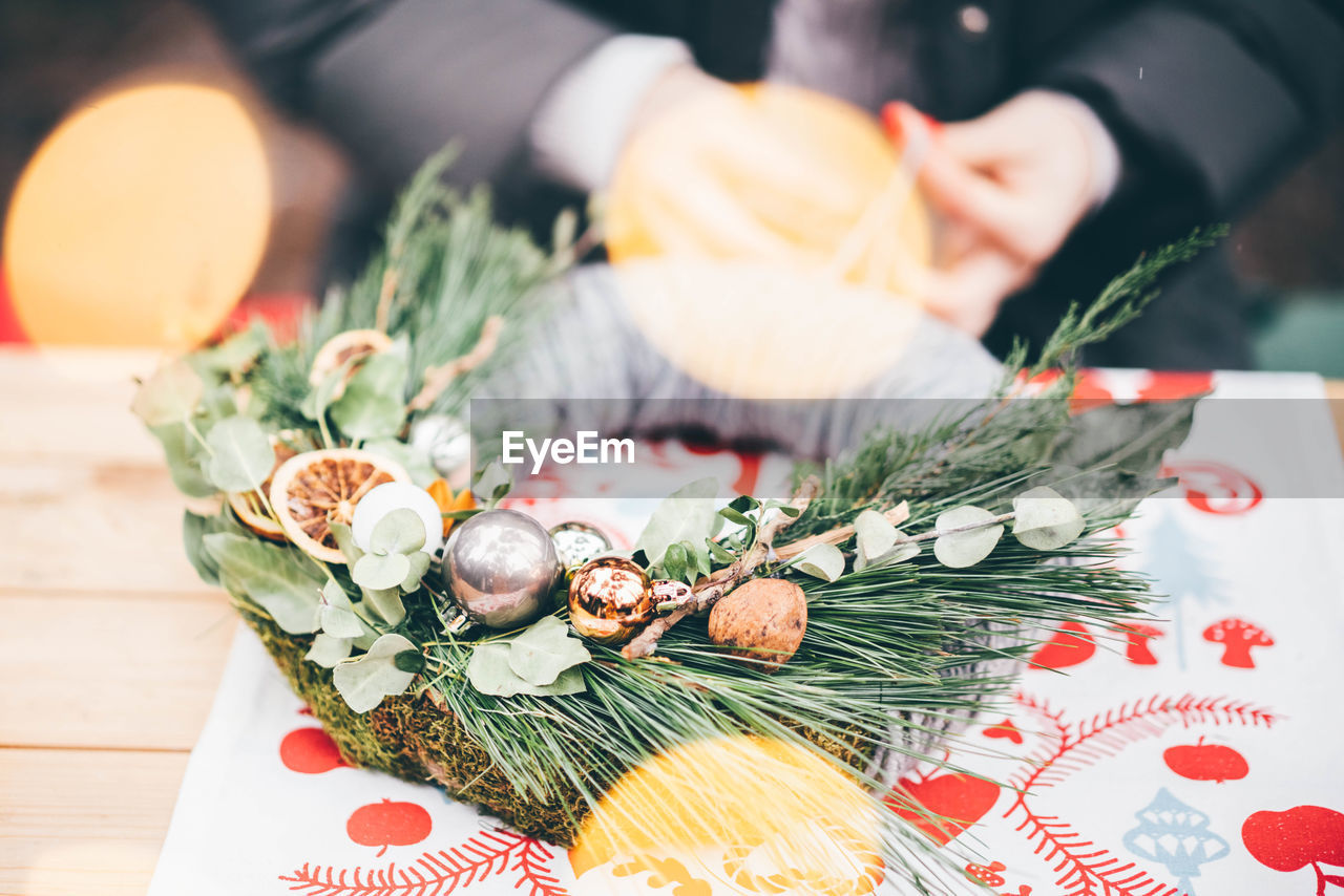 cropped hands of woman with christmas decorations on table