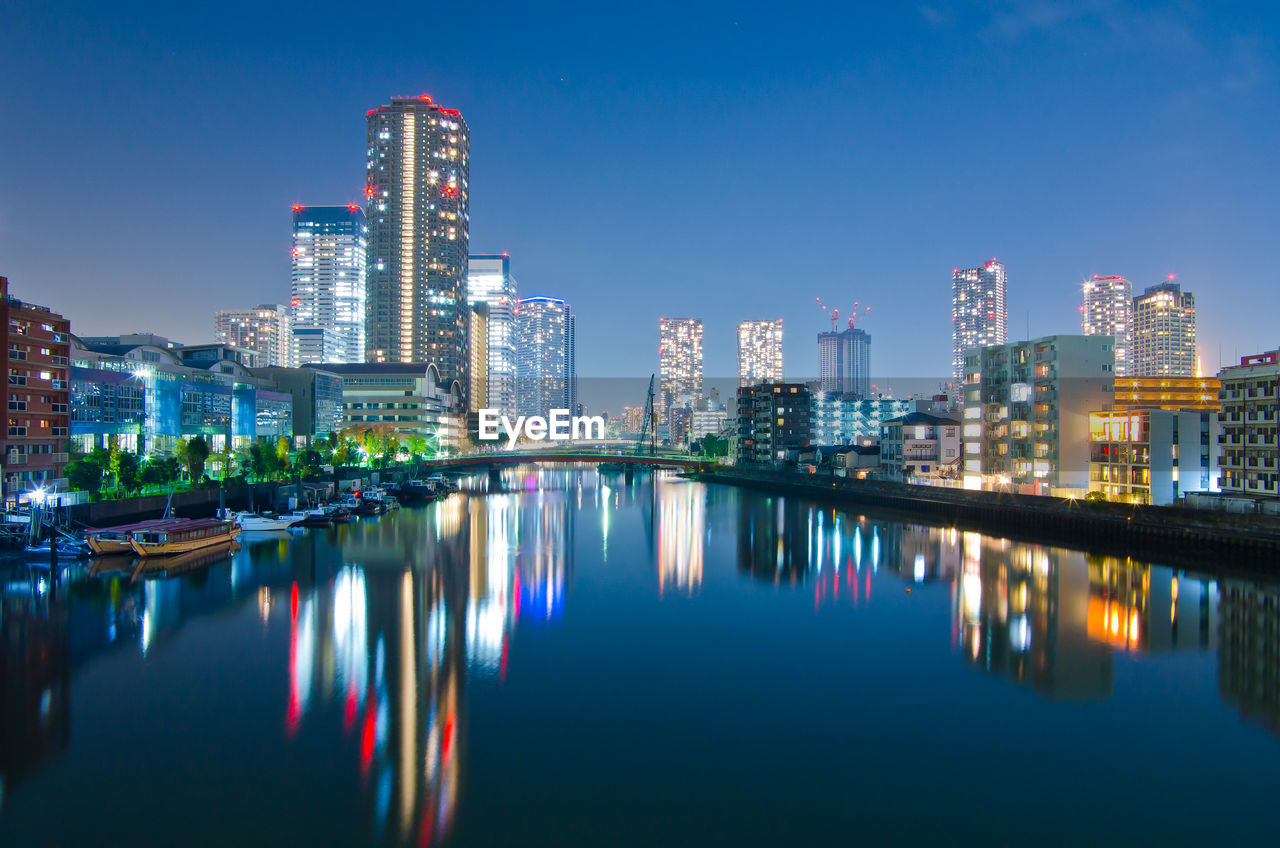 River by illuminated buildings against sky at night