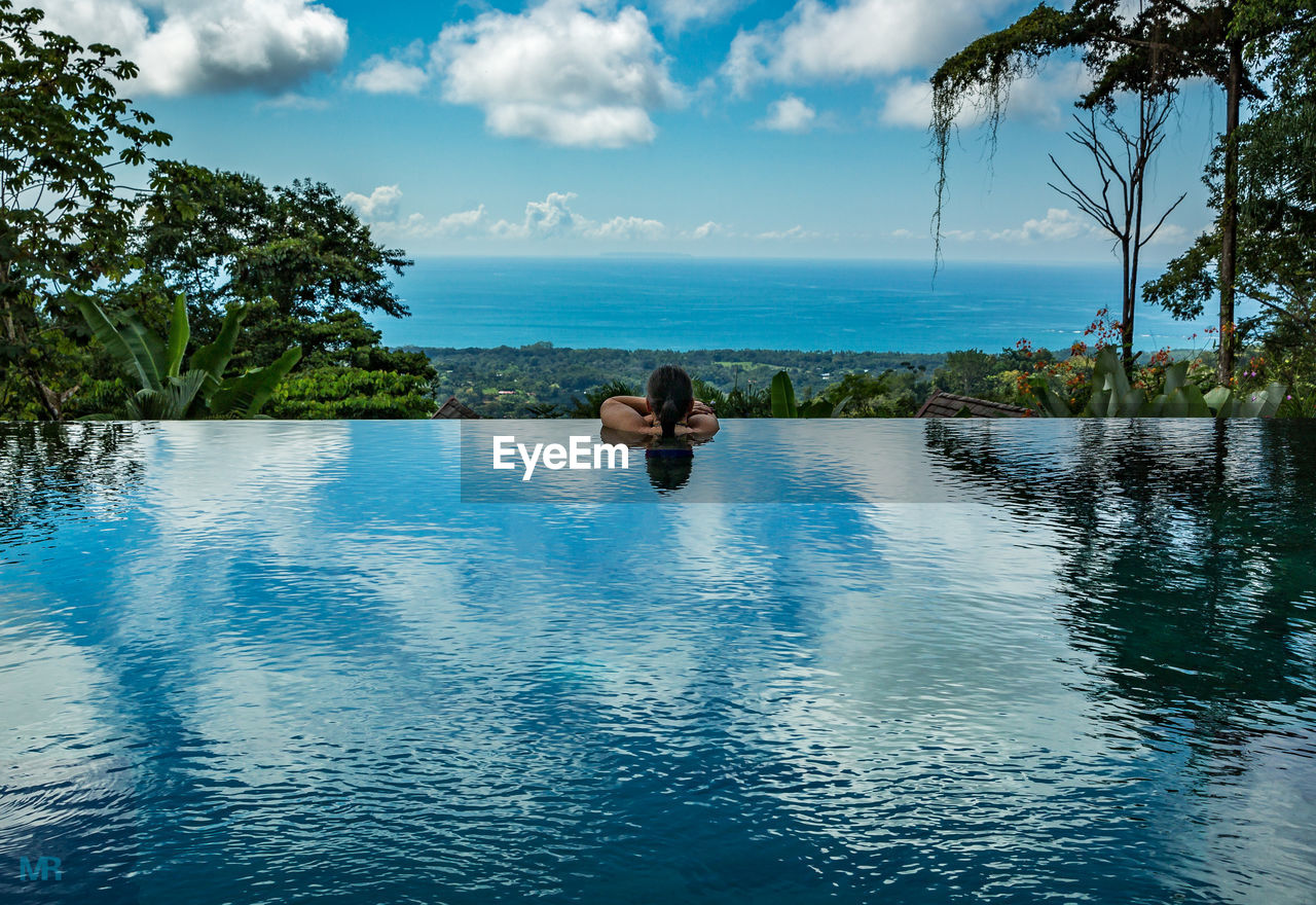 Rear view of woman in infinity pool