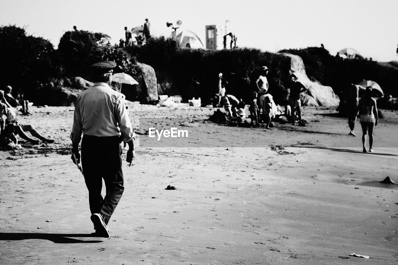 Man walking at sea shore against sky