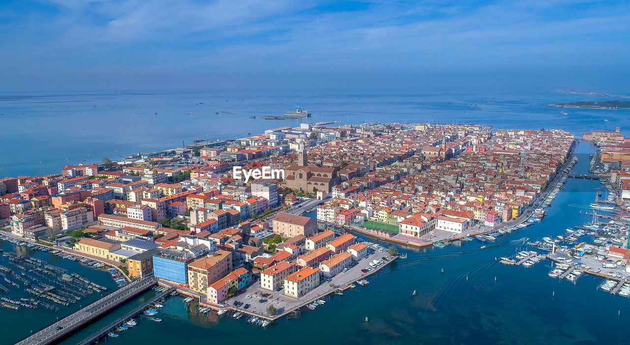 HIGH ANGLE VIEW OF SEA AND BUILDINGS AGAINST SKY